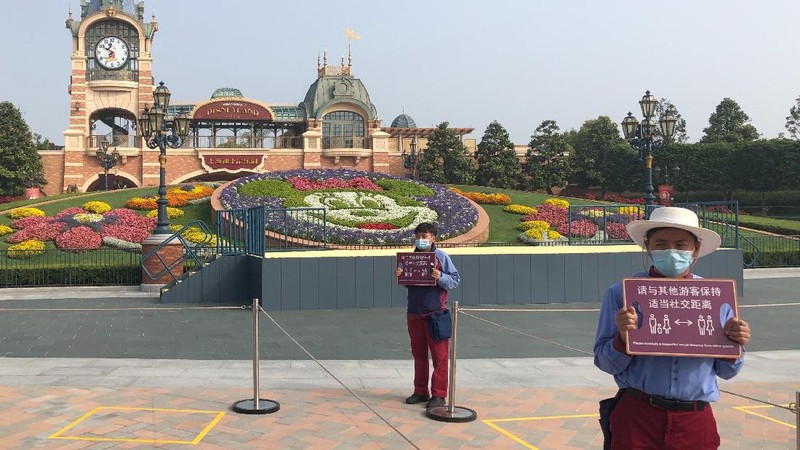 Visitors, wearing face masks, wait to enter the Disneyland theme park in Shanghai as it reopened, Monday, May 11, 2020. Visits will be limited initially and must be booked in advance, and the company said it will increase cleaning and require social distancing in lines for the various attractions. With warmer weather and new coronavirus cases and deaths falling to near-zero, China has been reopening tourist sites such as the Great Wall and the Forbidden City palace complex in Beijing.(AP Photo/Sam McNeil)
