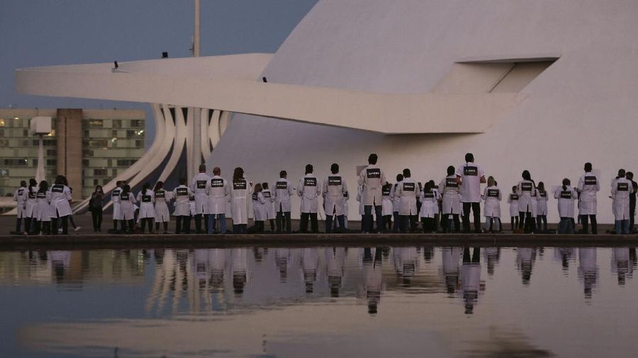 Nurses gather in front of the National Museum holding placards with the names of their colleagues who died in their fight against the new coronavirus pandemic, during a protest marking International Nurses Day, in Brasilia, Brazil, Tuesday, May 12, 2020. (AP Photo/Eraldo Peres)