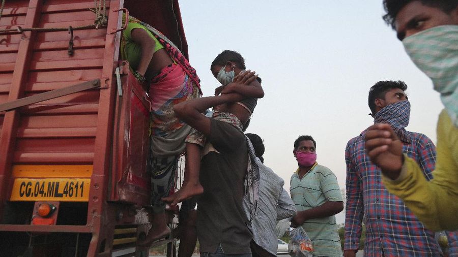 A migrant worker from Chhattisgarh state helps a child climb onto a truck to travel to their villages hundreds of miles away, during a nationwide lockdown to curb the spread of new coronavirus on the outskirts of Hyderabad, India, Tuesday, May 12, 2020. The lockdown that began March 25 sent an exodus of workers from its huge informal sector fleeing the cities to their ancestral homes in the countryside. Economists say unemployment reached 24.7% this week. (AP Photo/Mahesh Kumar A)