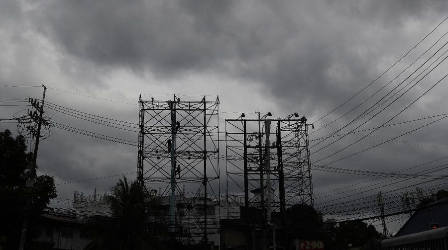 Dark clouds envelop the skies as workers fold a billboard to prepare for the coming of typhoon Vongfong in Manila, Philippines Thursday May, 14, 2020. The first typhoon to hit the country this year roared toward the eastern Philippines on Thursday as authorities work to evacuate tens of thousands of people while avoiding overcrowding in shelters that could spread the coronavirus. (AP Photo/Aaron Favila)