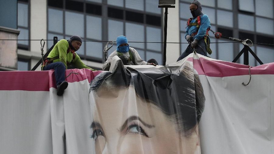Dark clouds envelop the skies as workers fold a billboard to prepare for the coming of typhoon Vongfong in Manila, Philippines Thursday May, 14, 2020. The first typhoon to hit the country this year roared toward the eastern Philippines on Thursday as authorities work to evacuate tens of thousands of people while avoiding overcrowding in shelters that could spread the coronavirus. (AP Photo/Aaron Favila)