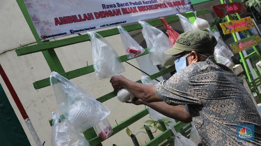 mengambil sembako yang digantung di rak kayu di kawasan Rawa Barat, Jakarta Selatan, Kamis, 14 Mei 2020. Warga Kelurahan Rawa Barat, Kebayoran Baru memiliki cara unik untuk berbagi dengan membuat rak kayu di sisi jalan yang dijadikan sebagai ruang bagi warga untuk menyumbangkan sembako, sayuran, masker, dan sebagainya antar sesama. (CNBC Indonesia/ Andrean Kristianto)