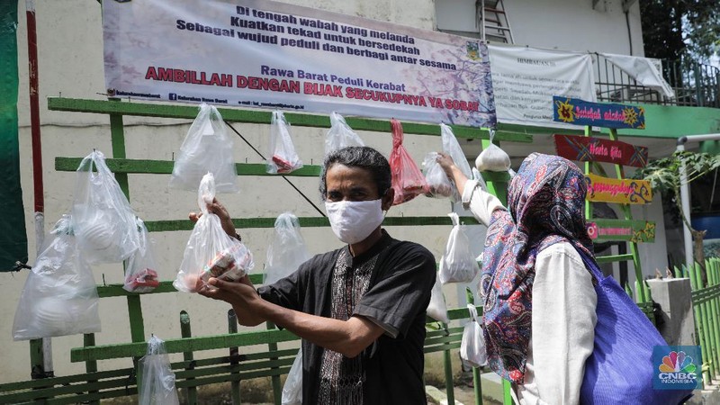 mengambil sembako yang digantung di rak kayu di kawasan Rawa Barat, Jakarta Selatan, Kamis, 14 Mei 2020. Warga Kelurahan Rawa Barat, Kebayoran Baru memiliki cara unik untuk berbagi dengan membuat rak kayu di sisi jalan yang dijadikan sebagai ruang bagi warga untuk menyumbangkan sembako, sayuran, masker, dan sebagainya antar sesama. (CNBC Indonesia/ Andrean Kristianto)