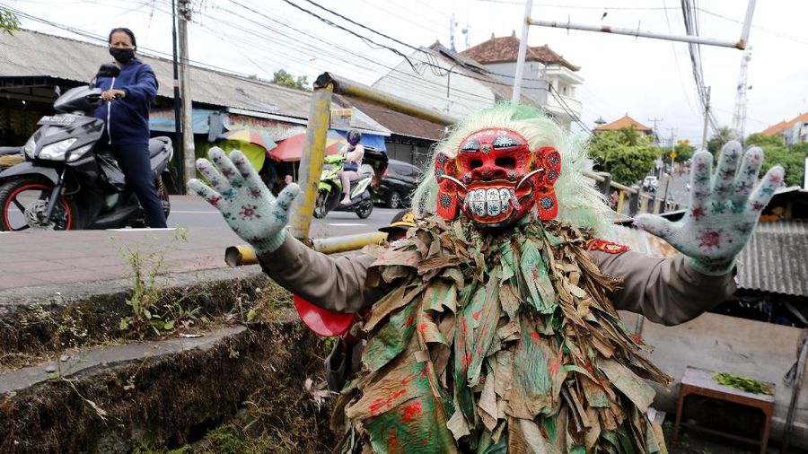 A police officer wearing a Balinese traditional mask, called celuluk, performs as the new coronavirus during a campaign to wear masks as a precaution against the virus outbreak at a market in Bali, Indonesia, Thursday, May 14, 2020. (AP Photo/Firdia Lisnawati)