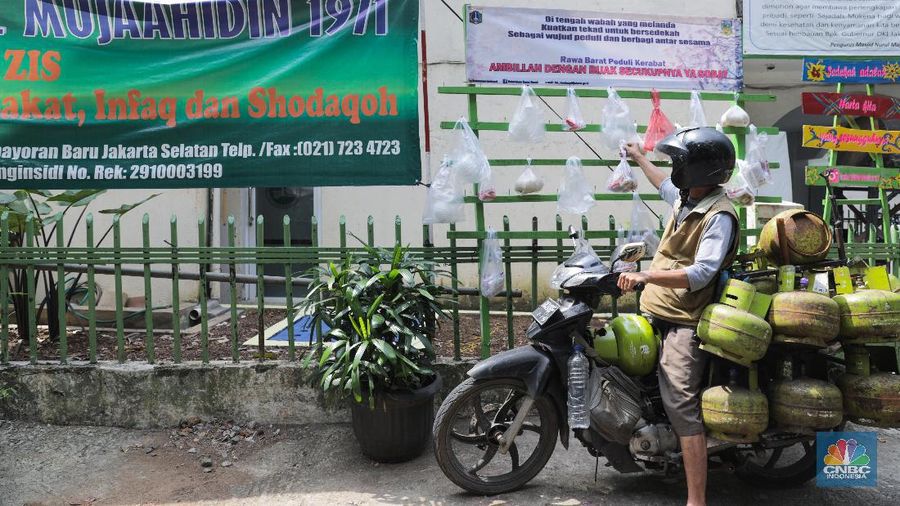 mengambil sembako yang digantung di rak kayu di kawasan Rawa Barat, Jakarta Selatan, Kamis, 14 Mei 2020. Warga Kelurahan Rawa Barat, Kebayoran Baru memiliki cara unik untuk berbagi dengan membuat rak kayu di sisi jalan yang dijadikan sebagai ruang bagi warga untuk menyumbangkan sembako, sayuran, masker, dan sebagainya antar sesama. (CNBC Indonesia/ Andrean Kristianto)