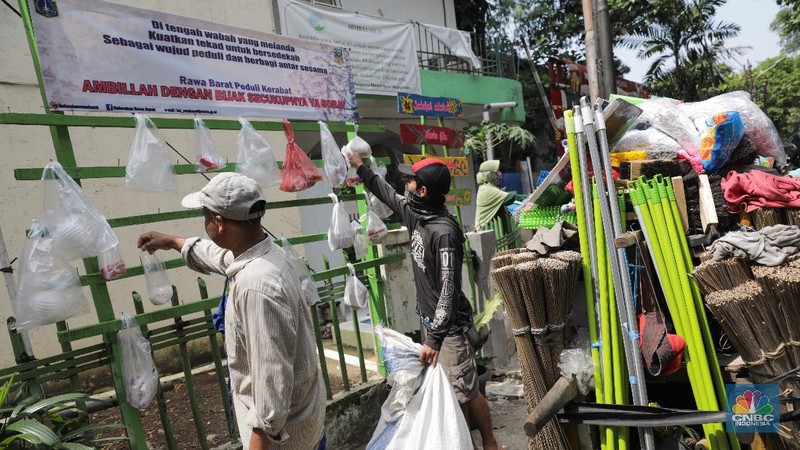 mengambil sembako yang digantung di rak kayu di kawasan Rawa Barat, Jakarta Selatan, Kamis, 14 Mei 2020. Warga Kelurahan Rawa Barat, Kebayoran Baru memiliki cara unik untuk berbagi dengan membuat rak kayu di sisi jalan yang dijadikan sebagai ruang bagi warga untuk menyumbangkan sembako, sayuran, masker, dan sebagainya antar sesama. (CNBC Indonesia/ Andrean Kristianto)