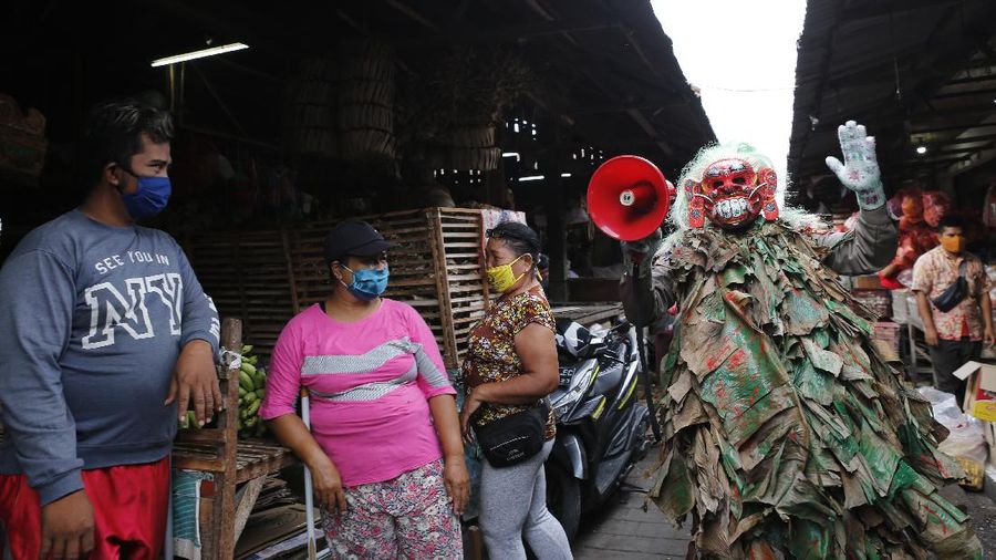 A police officer wearing a Balinese traditional mask, called celuluk, performs as the new coronavirus during a campaign to wear masks as a precaution against the virus outbreak at a market in Bali, Indonesia, Thursday, May 14, 2020. (AP Photo/Firdia Lisnawati)