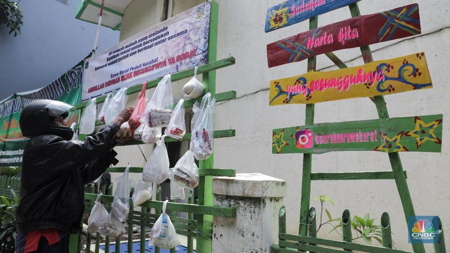 mengambil sembako yang digantung di rak kayu di kawasan Rawa Barat, Jakarta Selatan, Kamis, 14 Mei 2020. Warga Kelurahan Rawa Barat, Kebayoran Baru memiliki cara unik untuk berbagi dengan membuat rak kayu di sisi jalan yang dijadikan sebagai ruang bagi warga untuk menyumbangkan sembako, sayuran, masker, dan sebagainya antar sesama. (CNBC Indonesia/ Andrean Kristianto)