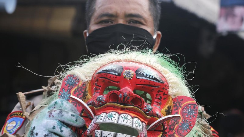 A police officer wearing a Balinese traditional mask, called celuluk, performs as the new coronavirus during a campaign to wear masks as a precaution against the virus outbreak at a market in Bali, Indonesia, Thursday, May 14, 2020. (AP Photo/Firdia Lisnawati)