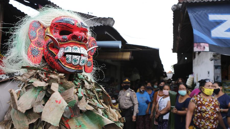 A police officer wearing a Balinese traditional mask, called celuluk, performs as the new coronavirus during a campaign to wear masks as a precaution against the virus outbreak at a market in Bali, Indonesia, Thursday, May 14, 2020. (AP Photo/Firdia Lisnawati)
