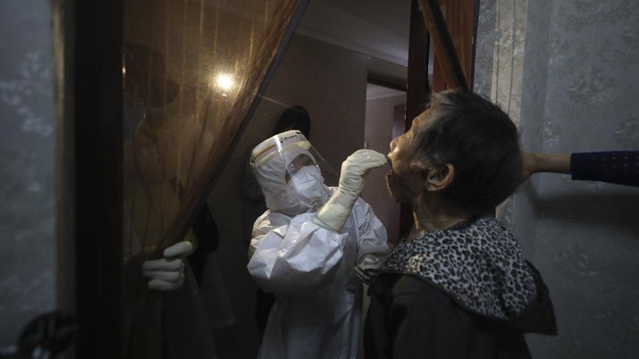 A medical worker takes a swab from a resident for the coronavirus test during home visits in Wuhan the epicenter of China's coronavirus outbreak in central China's Hubei province, Thursday, May 14, 2020. Some residential compounds in Wuhan have begun testing inhabitants for the coronavirus as a program to test everyone in the Chinese city of 11 million people in 10 days got underway. (Chinatopix via AP)