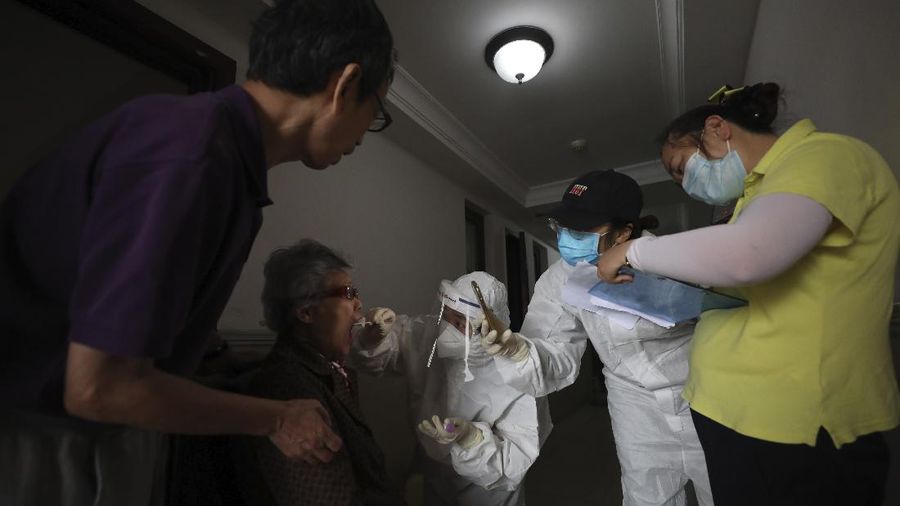 A medical worker takes a swab from a resident for the coronavirus test during home visits in Wuhan the epicenter of China's coronavirus outbreak in central China's Hubei province, Thursday, May 14, 2020. Some residential compounds in Wuhan have begun testing inhabitants for the coronavirus as a program to test everyone in the Chinese city of 11 million people in 10 days got underway. (Chinatopix via AP)