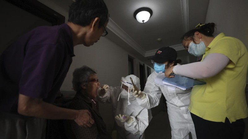 A medical worker takes a swab from a resident for the coronavirus test during home visits in Wuhan the epicenter of China's coronavirus outbreak in central China's Hubei province, Thursday, May 14, 2020. Some residential compounds in Wuhan have begun testing inhabitants for the coronavirus as a program to test everyone in the Chinese city of 11 million people in 10 days got underway. (Chinatopix via AP)