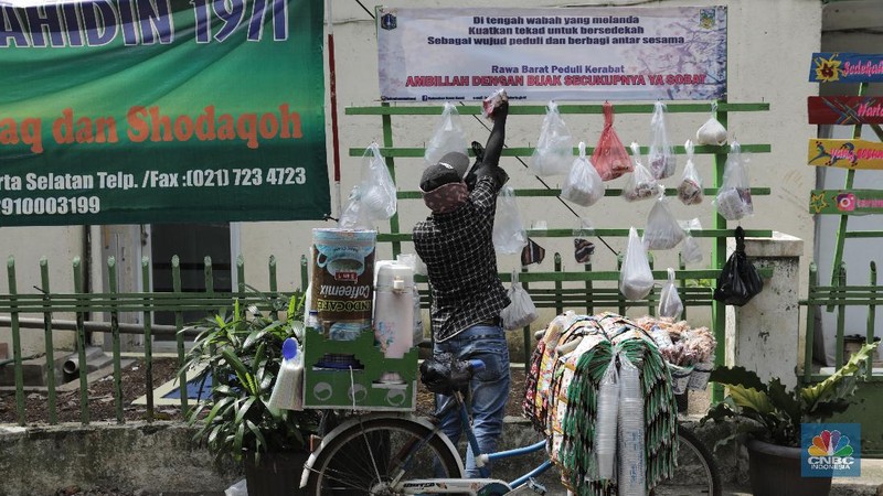 mengambil sembako yang digantung di rak kayu di kawasan Rawa Barat, Jakarta Selatan, Kamis, 14 Mei 2020. Warga Kelurahan Rawa Barat, Kebayoran Baru memiliki cara unik untuk berbagi dengan membuat rak kayu di sisi jalan yang dijadikan sebagai ruang bagi warga untuk menyumbangkan sembako, sayuran, masker, dan sebagainya antar sesama. (CNBC Indonesia/ Andrean Kristianto)