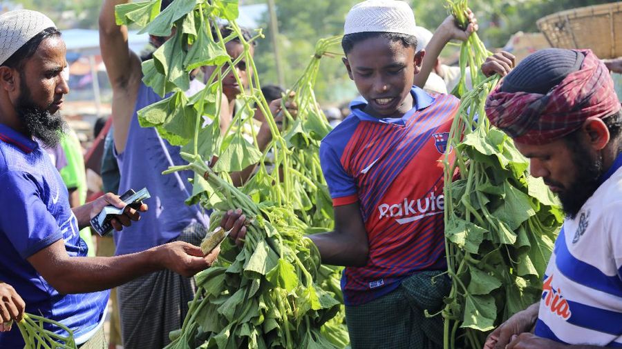 In this Friday, May 15, 2020, photo, a security officer makes announcements on a megaphone for people to observe social distancing at Kutupalong Rohingya camp bazar in Cox’s Bazar, Bangladesh. The first coronavirus case has been confirmed in the crowded camps for Rohingya refugees in southern Bangladesh, where more than 1 million are taking shelter. The infected Rohingya and a local Bangladeshi who lives in the Cox's Bazar district who also tested positive have been isolated, Mahbub Alam Talukder, the country’s refugee commissioner, said Thursday. (AP Photo/Suzauddin Rubel)