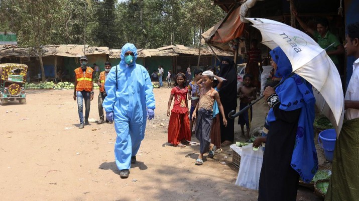 FILE - In this April 15, 2020, file photo, a health worker from an aid organization walks wearing a hazmat suit at the Kutupalong Rohingya refugee camp in Cox's Bazar, Bangladesh. Authorities on Thursday, May 14, 2020 reported the first coronavirus case in the crowded camps for Rohingya refugees in southern Bangladesh, where more than 1 million refugees have been sheltered, a Bangladeshi official and the United Nations said. (AP Photo/Shafiqur Rahman, File)