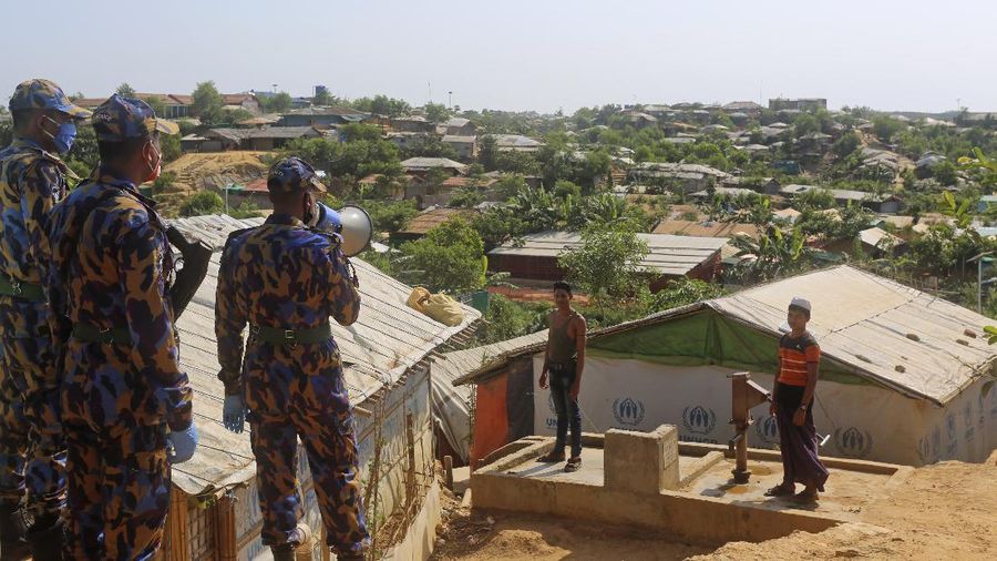 In this Friday, May 15, 2020, photo, a security officer makes announcements on a megaphone for people to observe social distancing at Kutupalong Rohingya camp bazar in Cox’s Bazar, Bangladesh. The first coronavirus case has been confirmed in the crowded camps for Rohingya refugees in southern Bangladesh, where more than 1 million are taking shelter. The infected Rohingya and a local Bangladeshi who lives in the Cox's Bazar district who also tested positive have been isolated, Mahbub Alam Talukder, the country’s refugee commissioner, said Thursday. (AP Photo/Suzauddin Rubel)
