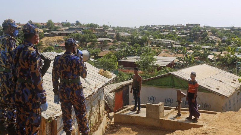 In this Friday, May 15, 2020, photo, a security officer makes announcements on a megaphone for people to observe social distancing at Kutupalong Rohingya camp bazar in Cox’s Bazar, Bangladesh. The first coronavirus case has been confirmed in the crowded camps for Rohingya refugees in southern Bangladesh, where more than 1 million are taking shelter. The infected Rohingya and a local Bangladeshi who lives in the Cox's Bazar district who also tested positive have been isolated, Mahbub Alam Talukder, the country’s refugee commissioner, said Thursday. (AP Photo/Suzauddin Rubel)