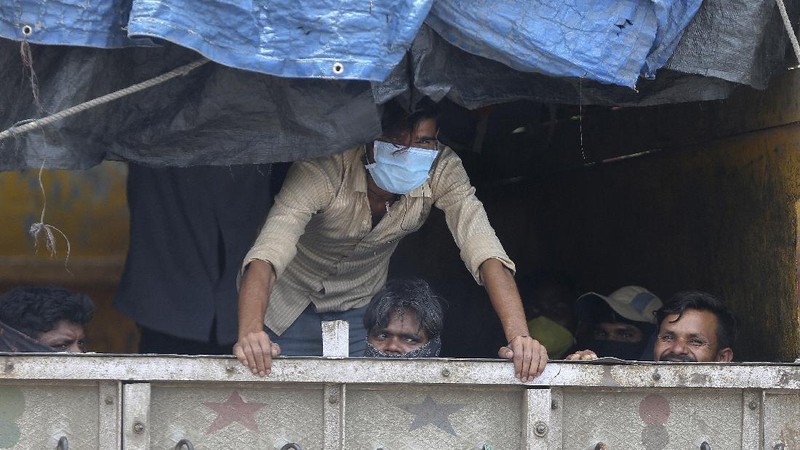 Migrant workers sit inside a truck, after they were stopped and directed towards a temporary shelter to register for free travel on a train, during lockdown to prevent the spread of new coronavirus on the outskirts of Hyderabad, India, Saturday, May 16, 2020. Tens of thousands of migrant laborers have been returning from big cities to their villages after losing jobs because of a countrywide lockdown imposed in late March to contain the spread of the coronavirus. (AP Photo/Mahesh Kumar A.)