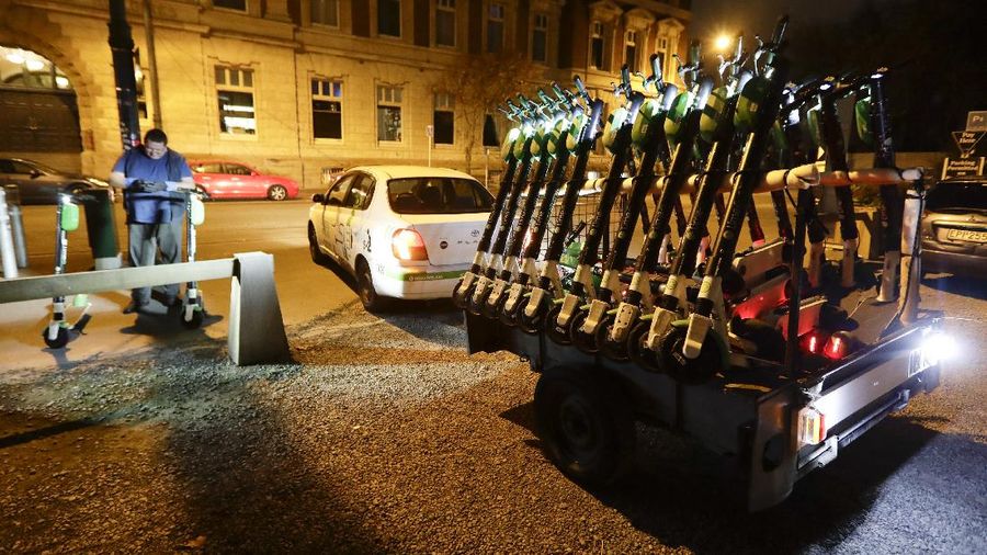 A worker places electric scooters back on the streets just past midnight in Christchurch, New Zealand, Thursday, May 14, 2020. New Zealand lifted most of its remaining lockdown restrictions from midnight Wednesday (noon Weds. GMT) as the country prepares for a new normal. Malls, retail stores and restaurants will reopen and many people will return to their workplaces. (AP Photo/Mark Baker)