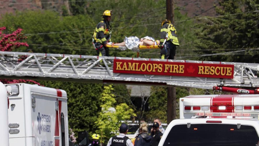 First responders attend to a person on a rooftop at the scene of a crash involving a Canadian Forces Snowbirds airplane in Kamloops, British Columbia, Sunday, May 17, 2020. (Brendan Kergin/Castanet Kamloops/The Canadian Press via AP)