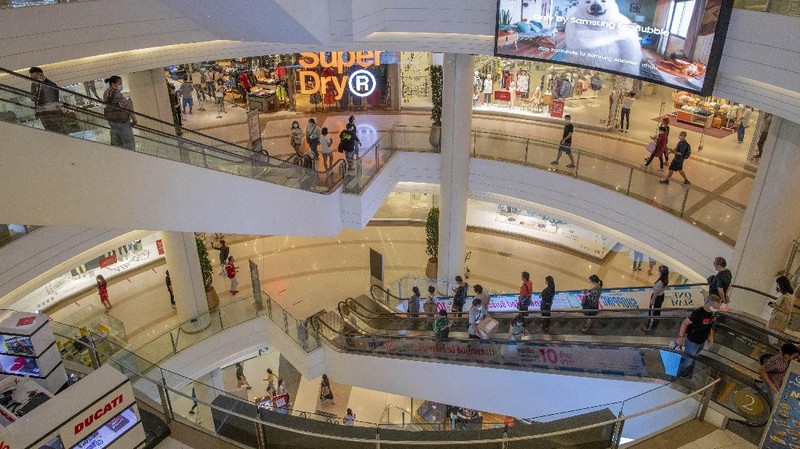 Patrons stand maintaining a physical distance at the entrance of the upmarket shopping mall Siam Paragon in Bangkok, Thailand, Sunday, May 17, 2020. Thai authorities allowed department stores, shopping malls and other businesses to reopen from Sunday, selectively easing restrictions meant to combat the coronavirus. (AP Photo/ Gemunu Amarasinghe)