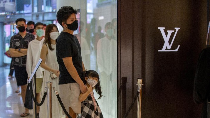 Patrons stand in a line to enter the Louis Vuitton shop at the upmarket shopping mall Siam Paragon in Bangkok, Thailand, Sunday, May 17, 2020. Thai authorities allowed department stores, shopping malls and other businesses to reopen from Sunday, selectively easing restrictions meant to combat the coronavirus. (AP Photo/ Gemunu Amarasinghe)