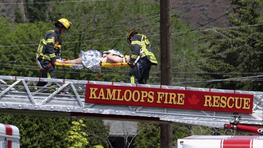 First responders attend to a person on a rooftop at the scene of a crash involving a Canadian Forces Snowbirds airplane in Kamloops, British Columbia, Sunday, May 17, 2020. (Brendan Kergin/Castanet Kamloops/The Canadian Press via AP)