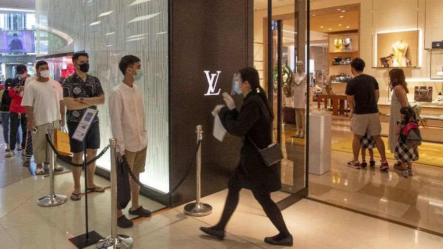 Patrons stand maintaining a physical distance at the entrance of the upmarket shopping mall Siam Paragon in Bangkok, Thailand, Sunday, May 17, 2020. Thai authorities allowed department stores, shopping malls and other businesses to reopen from Sunday, selectively easing restrictions meant to combat the coronavirus. (AP Photo/ Gemunu Amarasinghe)