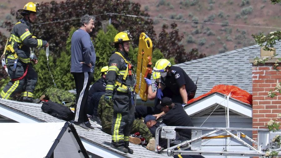 First responders attend to a person on a rooftop at the scene of a crash involving a Canadian Forces Snowbirds airplane in Kamloops, British Columbia, Sunday, May 17, 2020. (Brendan Kergin/Castanet Kamloops/The Canadian Press via AP)