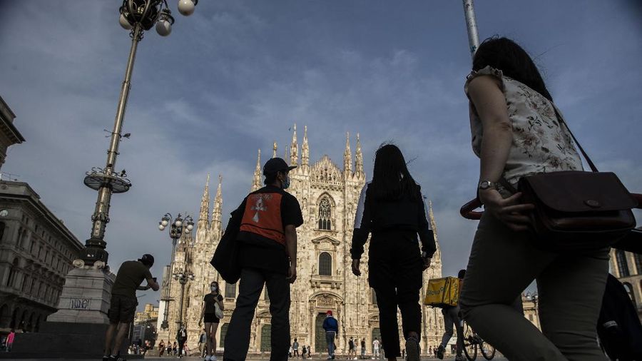 People walk at the Naviglio grande canal district in Milan, Italy, Monday, May 18, 2020. On Monday, Italians enjoyed a first day of regained freedoms, including being able to sit down at a cafe or restaurant, shop in all retail stores or attend church services such as Mass. (AP Photo/Luca Bruno)