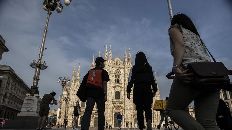 People walk at the Naviglio grande canal district in Milan, Italy, Monday, May 18, 2020. On Monday, Italians enjoyed a first day of regained freedoms, including being able to sit down at a cafe or restaurant, shop in all retail stores or attend church services such as Mass. (AP Photo/Luca Bruno)