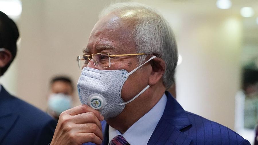 Former Malaysian Prime Minister Najib Razak, left, wearing a face mask has his body temperature checked by a security as he arrives at Kuala Lumpur high court in Kuala Lumpur, Malaysia, Tuesday, May 19, 2020. His trial linked to the multibillion-dollar looting of the 1MDB state investment fund resumed Tuesday. (AP Photo/Vincent Thian)