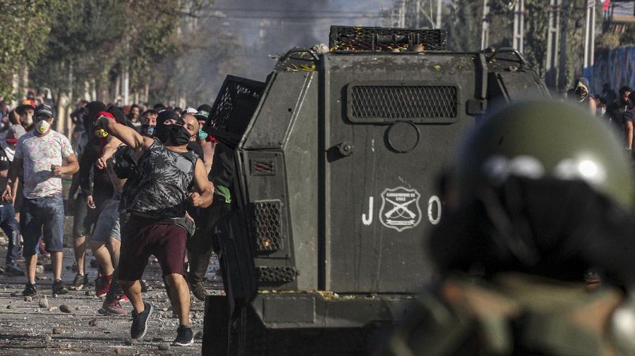 Demonstrators, some wearing protective face masks amid the new coronavirus pandemic, clash with the police during a protest demanding food aid from the government, at a poor neighborhood in Santiago, Chile, Monday, May 18, 2020. (AP Photo/Esteban Felix)