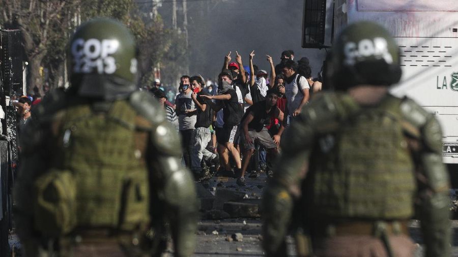 Demonstrators, some wearing protective face masks amid the new coronavirus pandemic, clash with the police during a protest demanding food aid from the government, at a poor neighborhood in Santiago, Chile, Monday, May 18, 2020. (AP Photo/Esteban Felix)