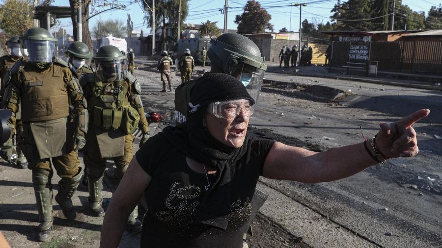 Demonstrators, some wearing protective face masks amid the new coronavirus pandemic, clash with the police during a protest demanding food aid from the government, at a poor neighborhood in Santiago, Chile, Monday, May 18, 2020. (AP Photo/Esteban Felix)