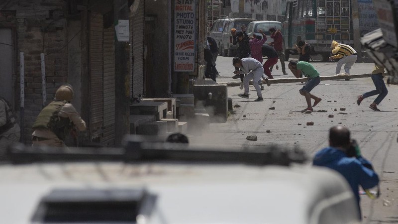 Kashmiri men cover their faces in response to the pellets fired by Indian police during a protest near the site of a gun battle in Srinagar, Indian controlled Kashmir, Tuesday, May 19, 2020. Indian government forces killed two rebels in disputed Kashmir on Tuesday and shut down cellphone and mobile internet services during subsequent anti-India protests, officials and residents said. (AP Photo/ Dar Yasin)
