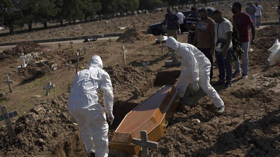 Cemetery workers in protective gear place the casket of 22-year-old COVID-19 victim Amanda da Silva into her grave site at the Caju cemetery in Rio de Janeiro, Brazil, Wednesday, May 20, 2020. (AP Photo/Silvia Izquierdo)