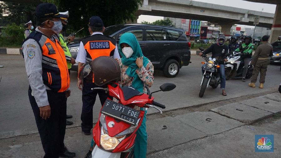 Petugas dishub dan polantas melakukan check point di Putaran jalan raya Kalimalang, Jakarta Timur, Jumat (22/5). Kepala UP Perparkiran DKI Jakarta Adji Kusambarto yang ditugaskan di check poin di putaran Jln Raya Kalimalang saat ditemui CNBC Indonesia mengatakan terkait dengan evaluasi sampai hari ini memang kita masih tahap sosialisasi kita tetap melakukan sosialisasi langsung pada pengguna jalan. Bagi mereka yang masuk dan keluar Jakarta harus menunjukkan SIKM bagi warga di luar Jabodetabek. Bagi warga yang tidak membawa SIKM nantinya akan diputar balikkan dan kembali ketempat asal mereka. Sampai sore ini ada sekitar 5 kendaraan roda empat yang disuruh putar balik dan 10 kendaraan roda dua. Sebagai besar yang disuruh putar balik diluar wilayah Jabodetabek. SIKM ini nantinya mulai berlaku mulai hari Senin. Seperti diketahui Pengendara yang melintas masuk atau keluar ibu kota di 12 titik checkpoint, wajib menunjukkan SIKM. Ketentuan ini sesuai Peraturan Gubernur Nomor 47 Tahun 2020 tentang Pembatasan Berpergian Keluar Masuk DKI Jakarta. SIKM diperuntukan bagi warga yang karena tugas dan pekerjaannya harus melakukan perjalanan dinas keluar dan/atau masuk wilayah DKI Jakarta atau Jabodetabek selama masa pandemi. (CNBC Indonesia/ Muhammad Sabki)