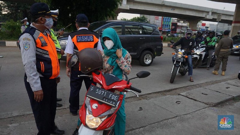 Petugas dishub dan polantas melakukan check point di Putaran jalan raya Kalimalang, Jakarta Timur, Jumat (22/5). Kepala UP Perparkiran DKI Jakarta Adji Kusambarto yang ditugaskan di check poin di putaran Jln Raya Kalimalang saat ditemui CNBC Indonesia mengatakan terkait dengan evaluasi sampai hari ini memang kita masih tahap sosialisasi kita tetap melakukan sosialisasi langsung pada pengguna jalan. Bagi mereka yang masuk dan keluar Jakarta harus menunjukkan SIKM bagi warga di luar Jabodetabek. Bagi warga yang tidak membawa SIKM nantinya akan diputar balikkan dan kembali ketempat asal mereka. Sampai sore ini ada sekitar 5 kendaraan roda empat yang disuruh putar balik dan 10 kendaraan roda dua. Sebagai besar yang disuruh putar balik diluar wilayah Jabodetabek. SIKM ini nantinya mulai berlaku mulai hari Senin. Seperti diketahui Pengendara yang melintas masuk atau keluar ibu kota di 12 titik checkpoint, wajib menunjukkan SIKM. Ketentuan ini sesuai Peraturan Gubernur Nomor 47 Tahun 2020 tentang Pembatasan Berpergian Keluar Masuk DKI Jakarta. SIKM diperuntukan bagi warga yang karena tugas dan pekerjaannya harus melakukan perjalanan dinas keluar dan/atau masuk wilayah DKI Jakarta atau Jabodetabek selama masa pandemi. (CNBC Indonesia/ Muhammad Sabki)