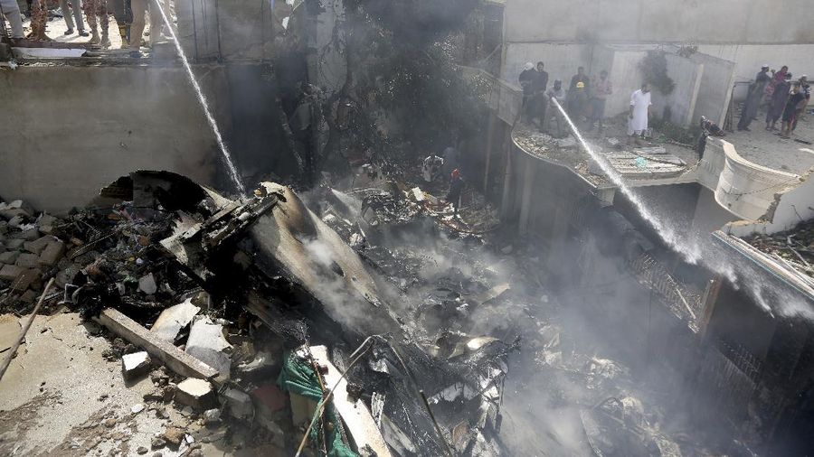 A firefighter tries to put out fire caused by plane crash in Karachi, Pakistan, Friday, May 22, 2020. An aviation official says a passenger plane belonging to state-run Pakistan International Airlines carrying more than 100 passengers and crew has crashed near the southern port city of Karachi. There were no immediate reports on the number of casualties. (AP Photo/Fareed Khan)