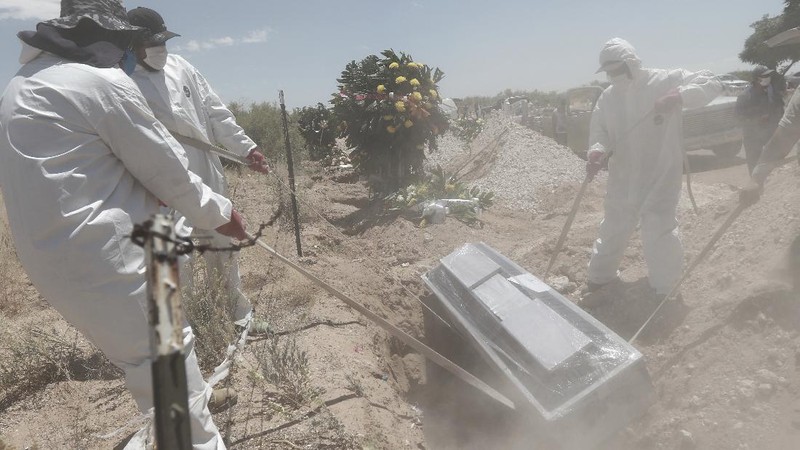 Workers wearing protective gear carry the plastic-wrapped coffin of a person who died from COVID-19 into the crematorium at San Cristobal Mausoleums in Ecatepec, Mexico State, part of the Mexico City metropolitan area, Thursday, May 21, 2020. When handling cases of confirmed or suspected COVID-19, crematorium workers wear protective suits, full-face respirators, and gloves, and maintain strict disinfection protocols. (AP Photo/Rebecca Blackwell)