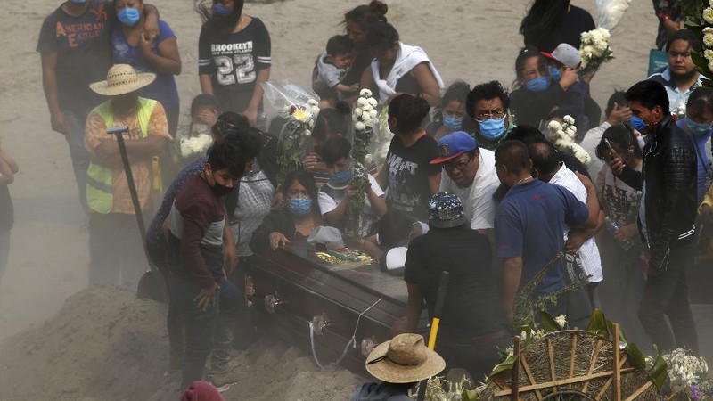 Workers wearing protective gear carry the plastic-wrapped coffin of a person who died from COVID-19 into the crematorium at San Cristobal Mausoleums in Ecatepec, Mexico State, part of the Mexico City metropolitan area, Thursday, May 21, 2020. When handling cases of confirmed or suspected COVID-19, crematorium workers wear protective suits, full-face respirators, and gloves, and maintain strict disinfection protocols. (AP Photo/Rebecca Blackwell)