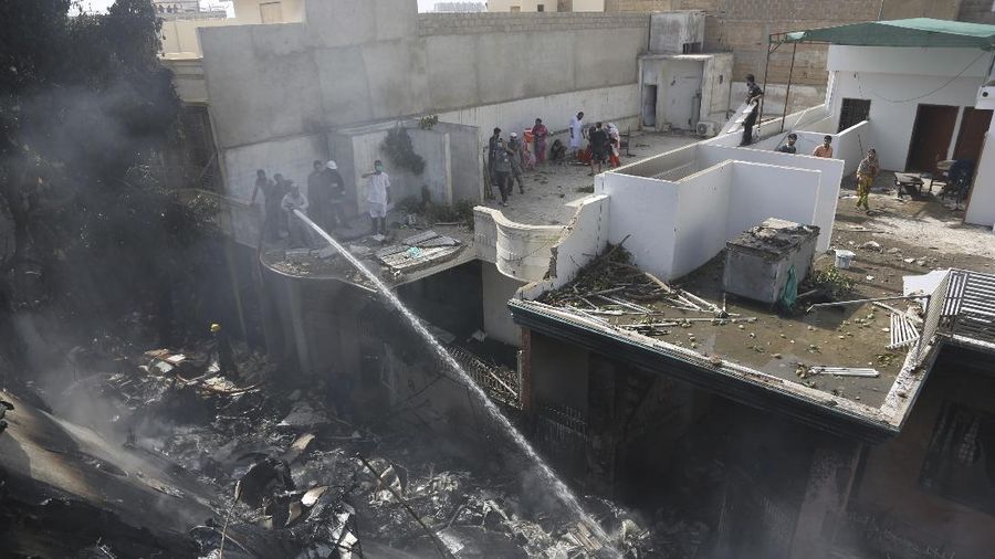 A firefighter tries to put out fire caused by plane crash in Karachi, Pakistan, Friday, May 22, 2020. An aviation official says a passenger plane belonging to state-run Pakistan International Airlines carrying more than 100 passengers and crew has crashed near the southern port city of Karachi. There were no immediate reports on the number of casualties. (AP Photo/Fareed Khan)