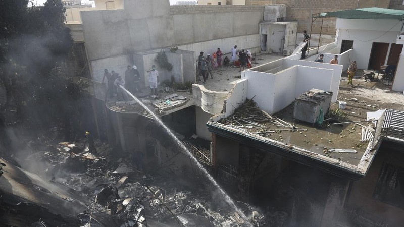 A firefighter tries to put out fire caused by plane crash in Karachi, Pakistan, Friday, May 22, 2020. An aviation official says a passenger plane belonging to state-run Pakistan International Airlines carrying more than 100 passengers and crew has crashed near the southern port city of Karachi. There were no immediate reports on the number of casualties. (AP Photo/Fareed Khan)
