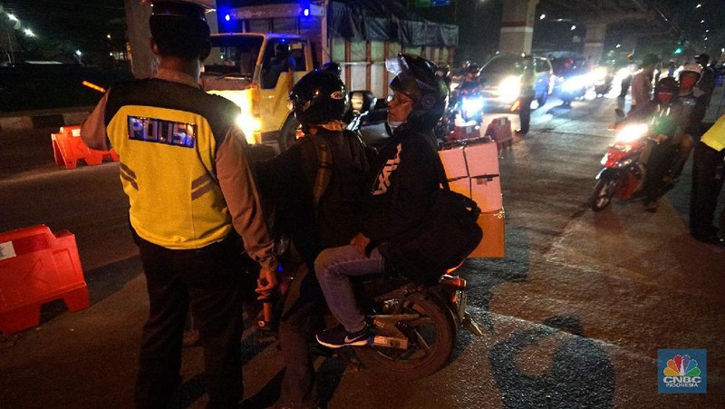 Petugas memeriksa kendaraan roda dua yang diduga untuk berpergian mudik di Jalan Raya Kalimalang, Jakarta Timur, Jumat (22/5). Dua hari jelang lebaran para pengendara motor masih ada yang nekat untuk pergi mudik. Petugas kepolisian dan Dishub memberhentikan motor yang memiliki muatan lebih. Pengendara motor diperiksa juga KTP asalnya. Jika ketahuan dari mereka mudik petugas menyuruh para pemudik motor untuk putar balik. Petugas kepolisian yang berjaga di check point jalan raya Kalimalang ini terus memantau, mengawasi dan melakukan pemeriksaan secara ketat agar pemudik yang berusaha keluar dari Jakarta bisa dihalau. Seperti diketahui Pengendara yang melintas masuk atau keluar ibu kota di 12 titik checkpoint, wajib menunjukkan SIKM. Ketentuan ini sesuai Peraturan Gubernur Nomor 47 Tahun 2020 tentang Pembatasan Berpergian Keluar Masuk DKI Jakarta. SIKM diperuntukan bagi warga yang karena tugas dan pekerjaannya harus melakukan perjalanan dinas keluar dan/atau masuk wilayah DKI Jakarta atau Jabodetabek selama masa pandemi.  (CNBC Indonesia/ Muhammad Sabki)