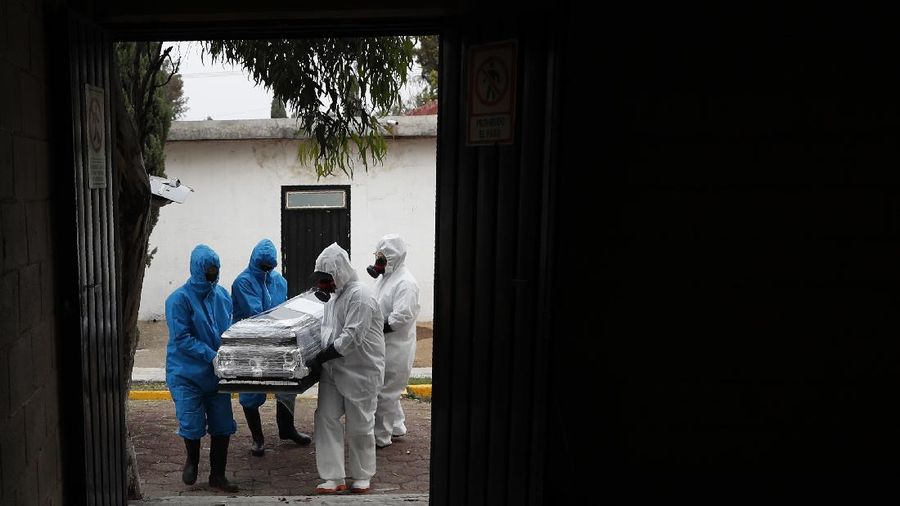 Workers wearing protective gear carry the plastic-wrapped coffin of a person who died from COVID-19 into the crematorium at San Cristobal Mausoleums in Ecatepec, Mexico State, part of the Mexico City metropolitan area, Thursday, May 21, 2020. When handling cases of confirmed or suspected COVID-19, crematorium workers wear protective suits, full-face respirators, and gloves, and maintain strict disinfection protocols. (AP Photo/Rebecca Blackwell)