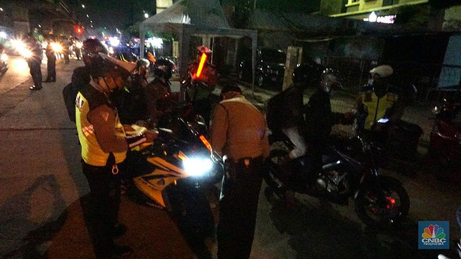 Petugas memeriksa kendaraan roda dua yang diduga untuk berpergian mudik di Jalan Raya Kalimalang, Jakarta Timur, Jumat (22/5). Dua hari jelang lebaran para pengendara motor masih ada yang nekat untuk pergi mudik. Petugas kepolisian dan Dishub memberhentikan motor yang memiliki muatan lebih. Pengendara motor diperiksa juga KTP asalnya. Jika ketahuan dari mereka mudik petugas menyuruh para pemudik motor untuk putar balik. Petugas kepolisian yang berjaga di check point jalan raya Kalimalang ini terus memantau, mengawasi dan melakukan pemeriksaan secara ketat agar pemudik yang berusaha keluar dari Jakarta bisa dihalau. Seperti diketahui Pengendara yang melintas masuk atau keluar ibu kota di 12 titik checkpoint, wajib menunjukkan SIKM. Ketentuan ini sesuai Peraturan Gubernur Nomor 47 Tahun 2020 tentang Pembatasan Berpergian Keluar Masuk DKI Jakarta. SIKM diperuntukan bagi warga yang karena tugas dan pekerjaannya harus melakukan perjalanan dinas keluar dan/atau masuk wilayah DKI Jakarta atau Jabodetabek selama masa pandemi.  (CNBC Indonesia/ Muhammad Sabki)