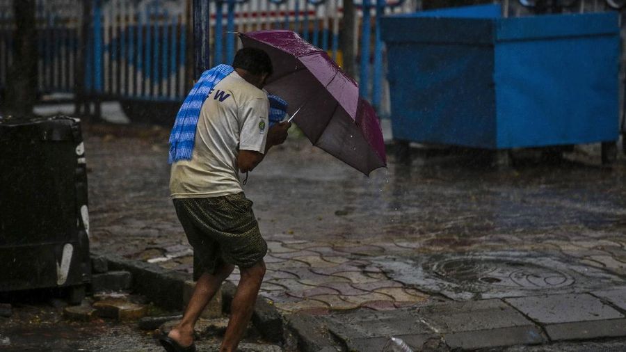 A man makes his way tpast a tree fallen in the middle of a road after Cyclone Amphan hit the region in Kolkata, India, Thursday, May 21, 2020. A powerful cyclone ripped through densely populated coastal India and Bangladesh, blowing off roofs and whipping up waves that swallowed embankments and bridges and left entire villages without access to fresh water, electricity and communications. (AP Photo/Bikas Das)