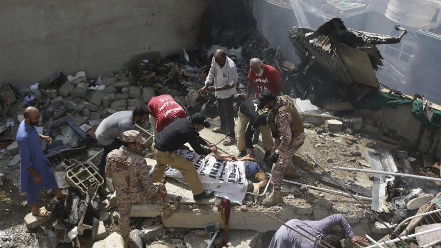 A firefighter tries to put out fire caused by plane crash in Karachi, Pakistan, Friday, May 22, 2020. An aviation official says a passenger plane belonging to state-run Pakistan International Airlines carrying more than 100 passengers and crew has crashed near the southern port city of Karachi. There were no immediate reports on the number of casualties. (AP Photo/Fareed Khan)